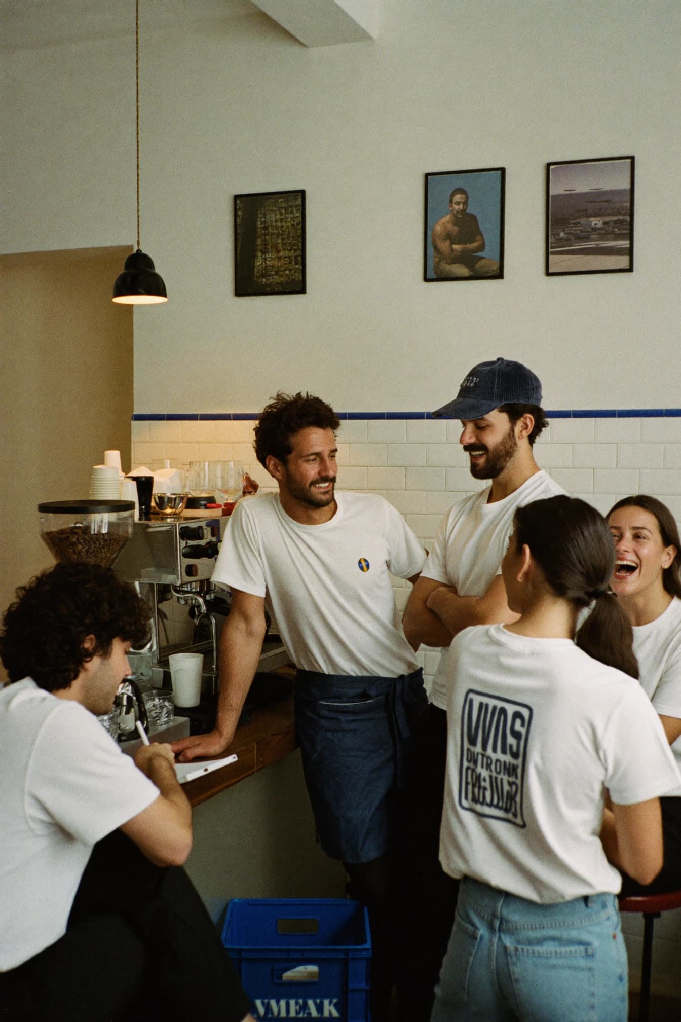 A café team talking together behind the counter at the espresso machine.